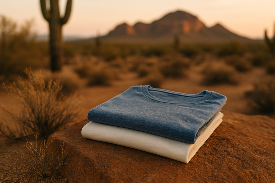 Stack of organic cotton and recycled polyester blend t-shirts in Arizona desert landscape with mountains and cactus at sunset.