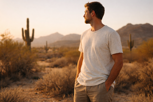 Man wearing a lightweight, sustainable cotton t-shirt standing in the Arizona desert at golden hour, with saguaro cacti and mountains in the background.